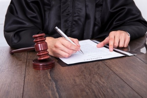 Close up of a hand signing the final papers for a divorce decree